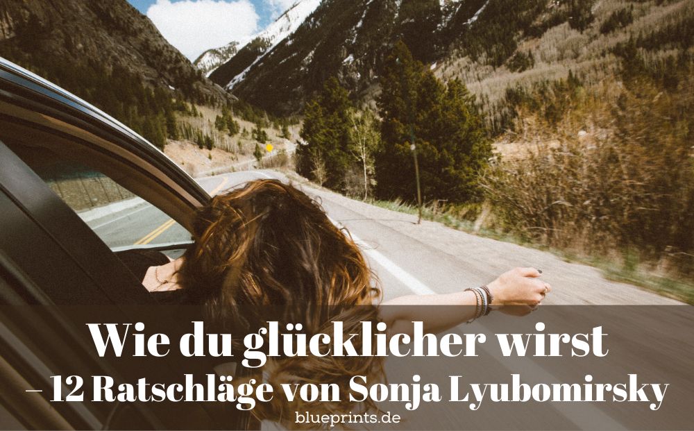 Frau hält den Kopf aus dem Autofenster und freut sich.